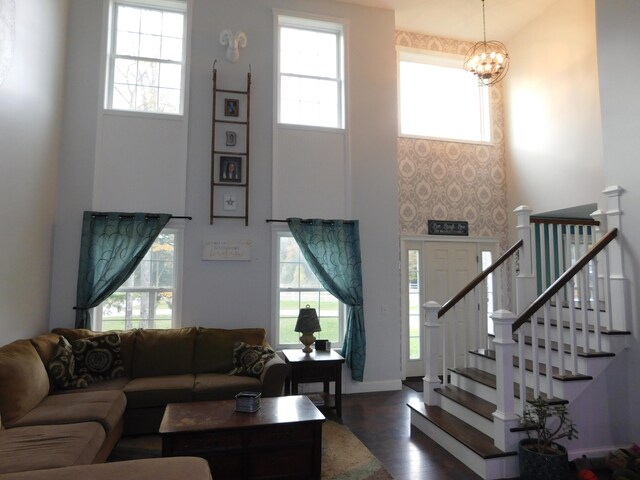 living area featuring an inviting chandelier, stairway, dark wood finished floors, and a wealth of natural light