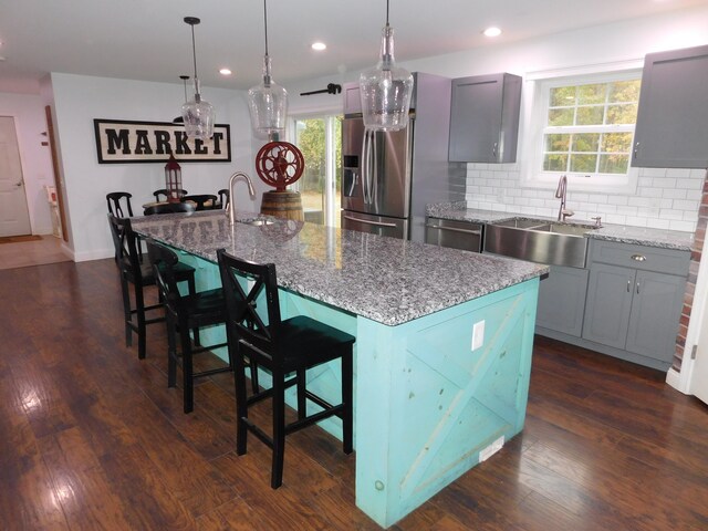 kitchen featuring dark wood-style floors, decorative backsplash, stainless steel appliances, and a sink