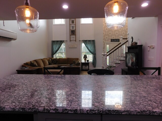 kitchen with a wall unit AC, recessed lighting, a towering ceiling, and decorative light fixtures