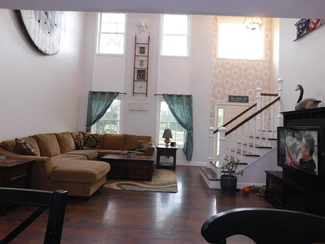 living area featuring stairway, wood finished floors, a towering ceiling, and baseboards