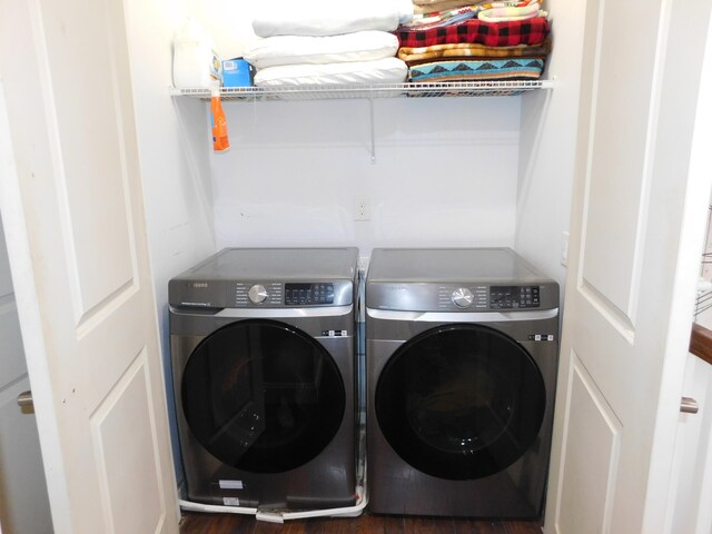 clothes washing area with washer and dryer, laundry area, and wood finished floors