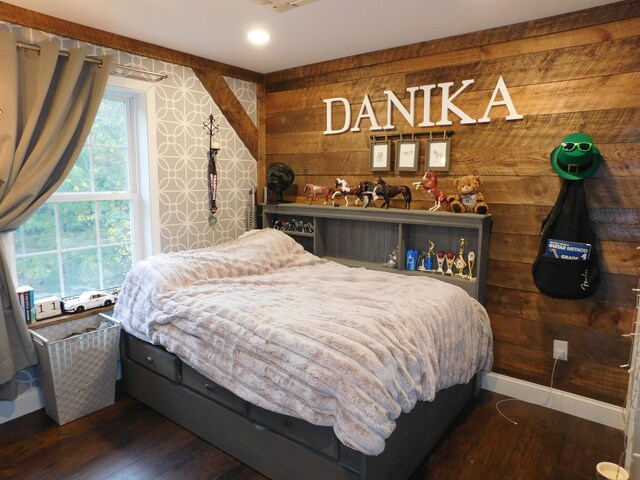 bedroom with wooden walls, baseboards, and wood finished floors