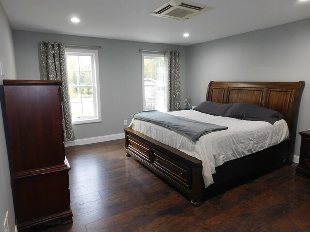 bedroom with multiple windows, dark wood finished floors, visible vents, and baseboards