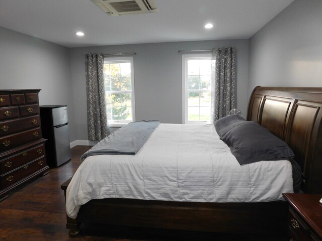 bedroom featuring freestanding refrigerator, multiple windows, dark wood finished floors, and visible vents