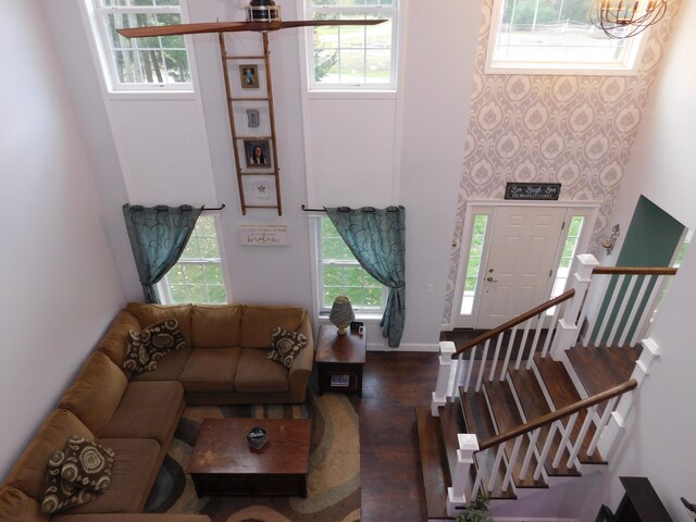 living area with a healthy amount of sunlight, a high ceiling, and wood finished floors