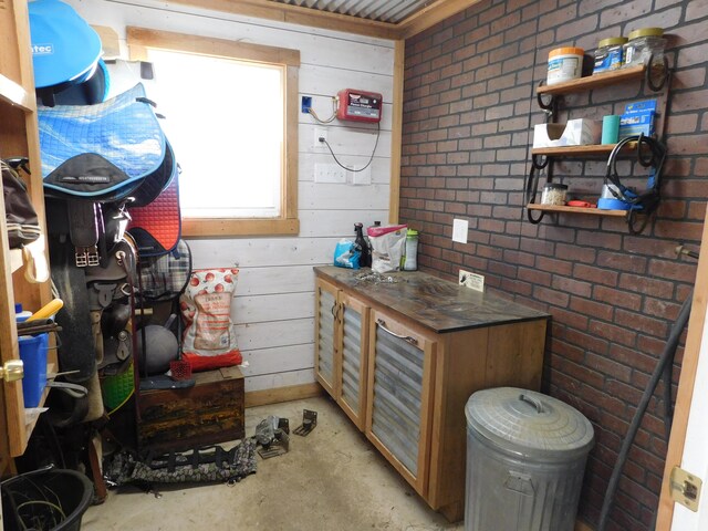 interior space featuring wooden walls, brick wall, and concrete floors