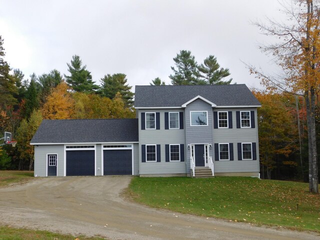 colonial house with a garage, a front yard, roof with shingles, and aphalt driveway