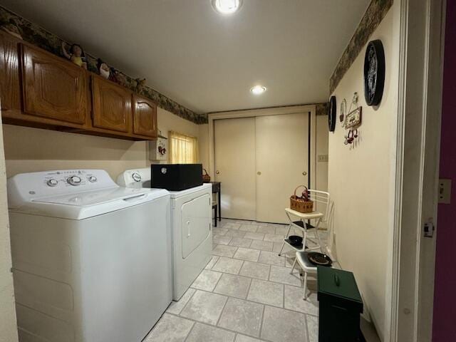 clothes washing area featuring cabinets, light tile patterned flooring, and washer and dryer