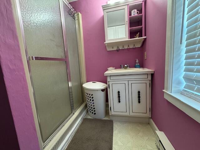 bathroom featuring a baseboard heating unit, vanity, and a shower with door