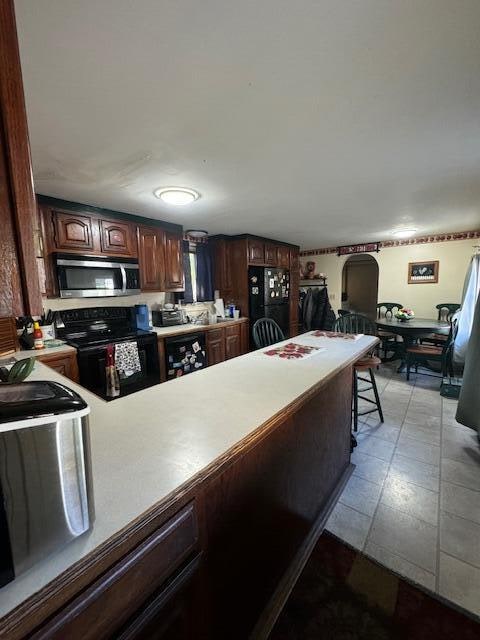 kitchen with light tile patterned flooring, wine cooler, black appliances, and sink