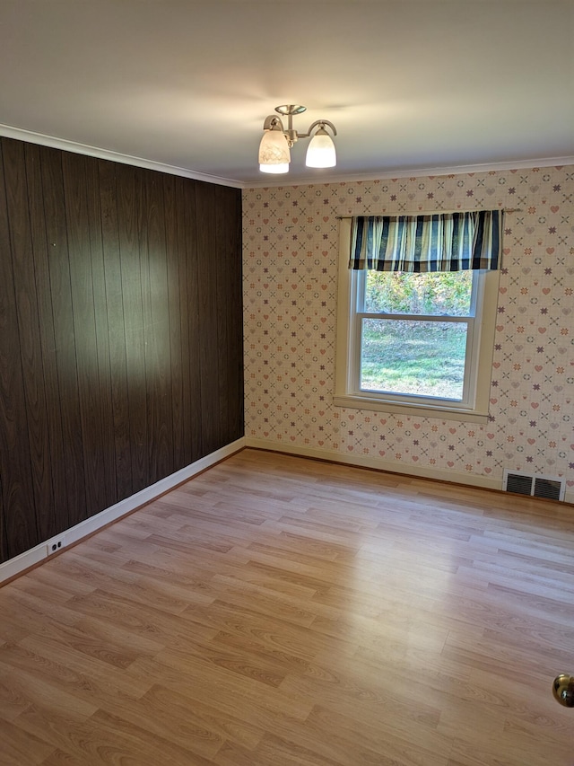 empty room with ornamental molding and light hardwood / wood-style flooring