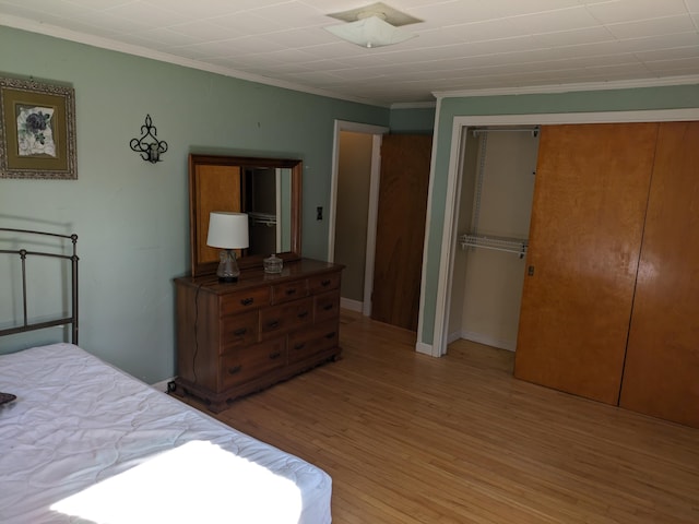 bedroom featuring crown molding, light wood finished floors, and a closet