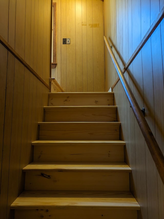 stairway featuring wooden walls