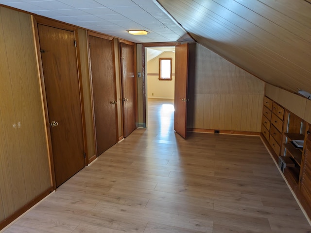 bonus room featuring light hardwood / wood-style flooring, wooden walls, and lofted ceiling