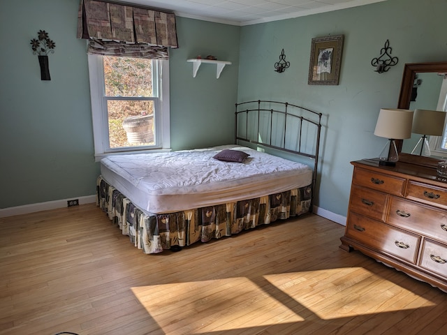 bedroom featuring ornamental molding and light hardwood / wood-style flooring