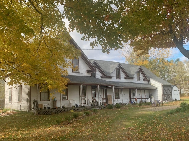 view of front of home featuring covered porch, a storage unit, and a front lawn