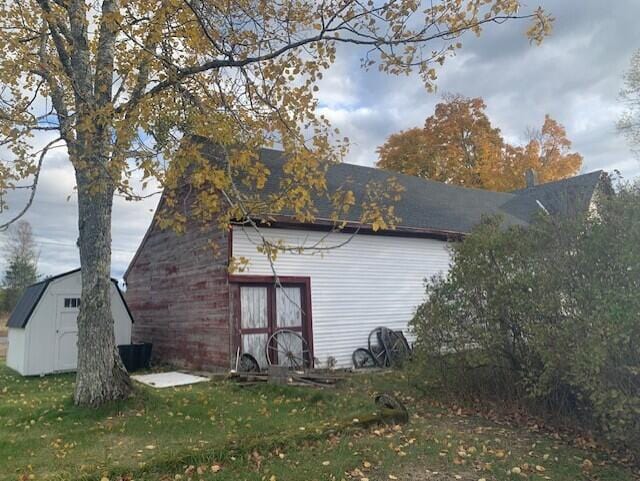 view of side of home featuring a storage unit and a lawn