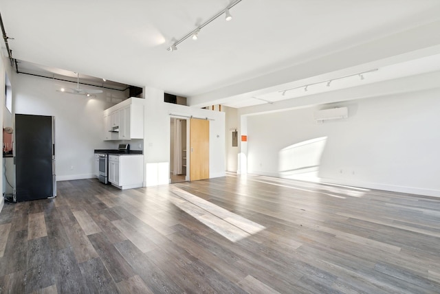 unfurnished living room featuring hardwood / wood-style floors, a wall mounted air conditioner, and rail lighting