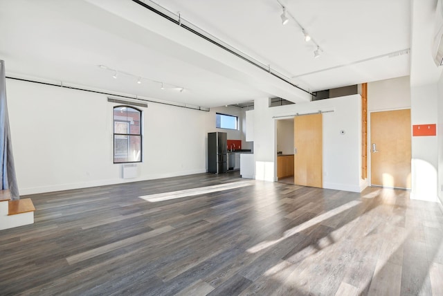 interior space with a barn door, hardwood / wood-style floors, and rail lighting