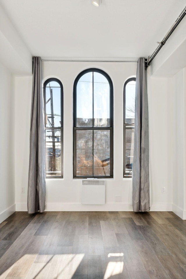 unfurnished room featuring hardwood / wood-style floors and radiator heating unit