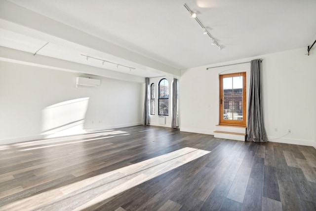 empty room featuring dark hardwood / wood-style floors, an AC wall unit, and track lighting