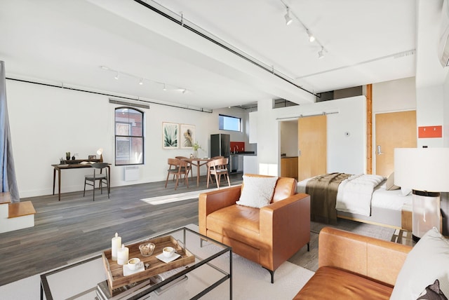 living room with wood-type flooring, a barn door, and rail lighting