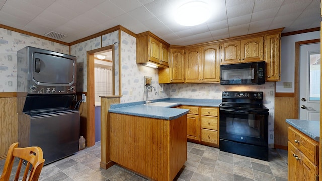 kitchen featuring stacked washer / dryer, crown molding, black appliances, and sink