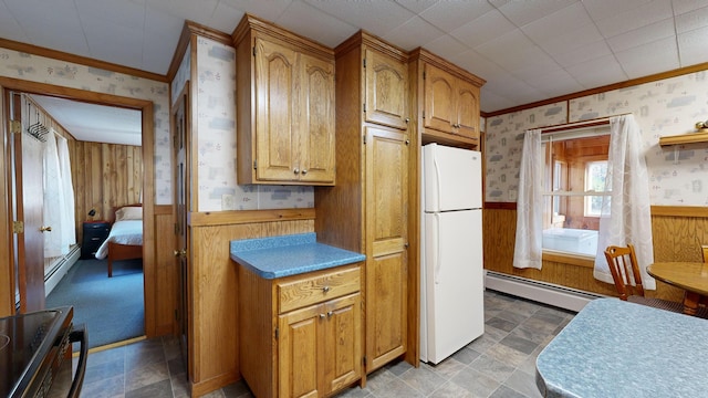 kitchen featuring baseboard heating, ornamental molding, wooden walls, and white refrigerator