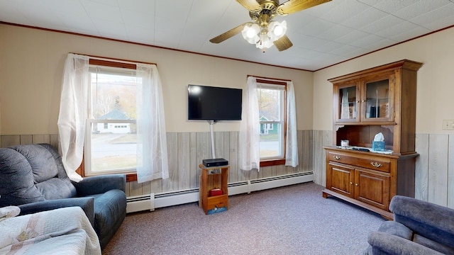 carpeted living room with wood walls, a baseboard radiator, ornamental molding, and ceiling fan