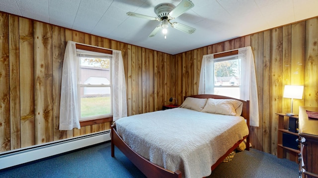 carpeted bedroom with ceiling fan, multiple windows, a baseboard radiator, and wood walls