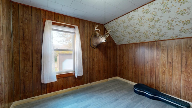 unfurnished room featuring lofted ceiling, wood walls, and light wood-type flooring