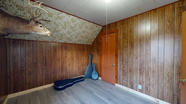 interior space with wood walls, lofted ceiling, and light wood-type flooring