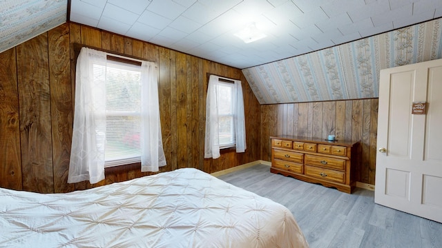 bedroom featuring wooden walls, vaulted ceiling, and wood-type flooring