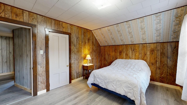 bedroom with wood walls, wood-type flooring, and lofted ceiling