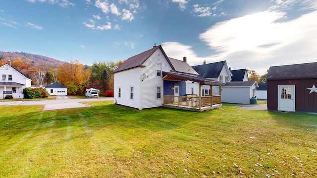 back of property with a storage shed, a deck, and a lawn