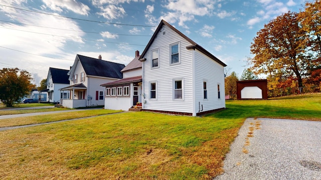 view of front of house featuring a front yard, a garage, and an outbuilding