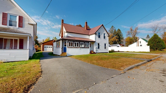 view of property with a garage, a front lawn, and an outbuilding