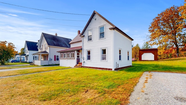 view of front facade with a garage, a front lawn, and an outbuilding