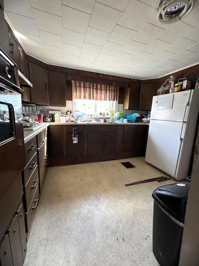 kitchen featuring dark brown cabinetry and white refrigerator