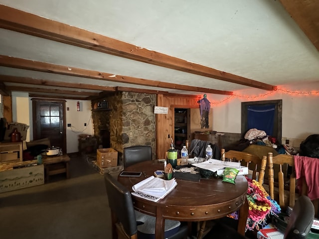 dining room featuring a stone fireplace and beam ceiling