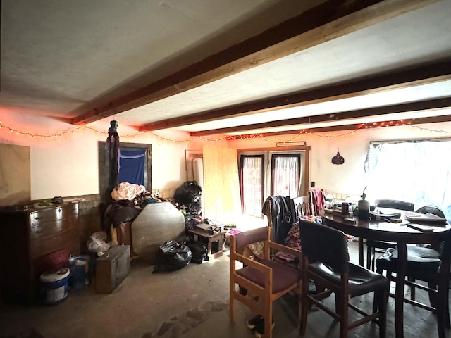 dining area featuring beam ceiling and concrete flooring