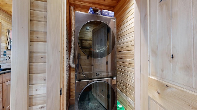 laundry area with wood ceiling, stacked washer / dryer, and wooden walls