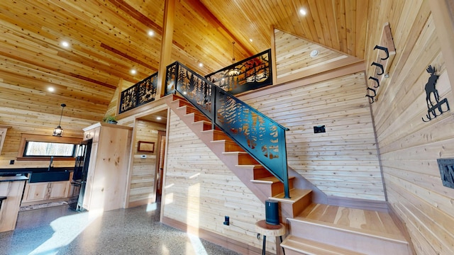 stairway with beam ceiling, sink, high vaulted ceiling, wooden walls, and wood ceiling