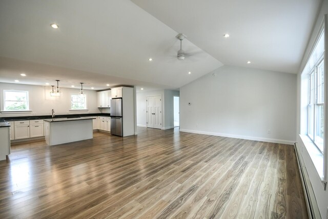 LOT8 Ward Rd, Sebago, ME 04029 - unfurnished living room with a baseboard radiator, wood finished floors, recessed lighting, lofted ceiling, and a sink