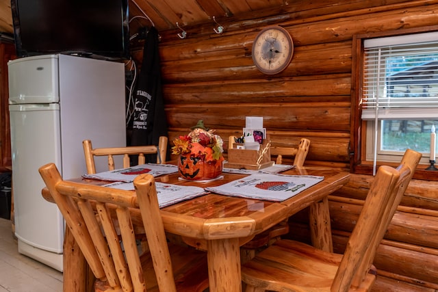 dining room featuring light hardwood / wood-style flooring, rustic walls, and wooden ceiling