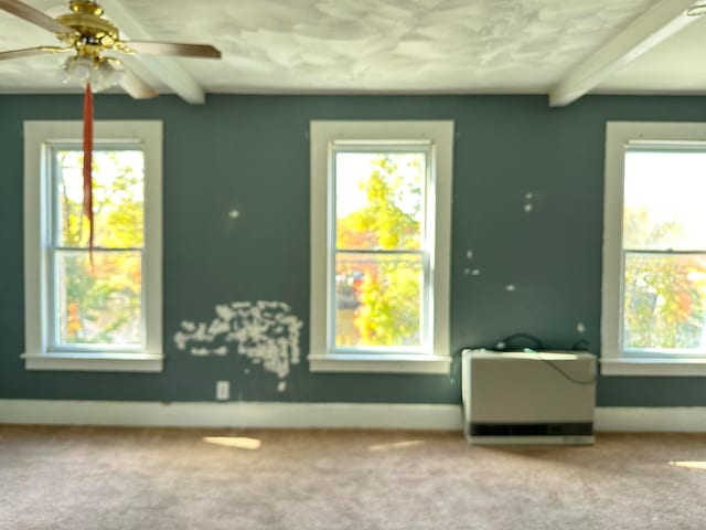 carpeted spare room featuring beamed ceiling and ceiling fan