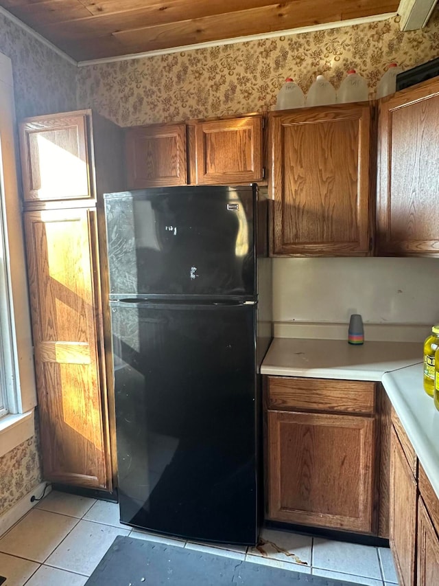 kitchen featuring wood ceiling, light tile patterned floors, and black refrigerator