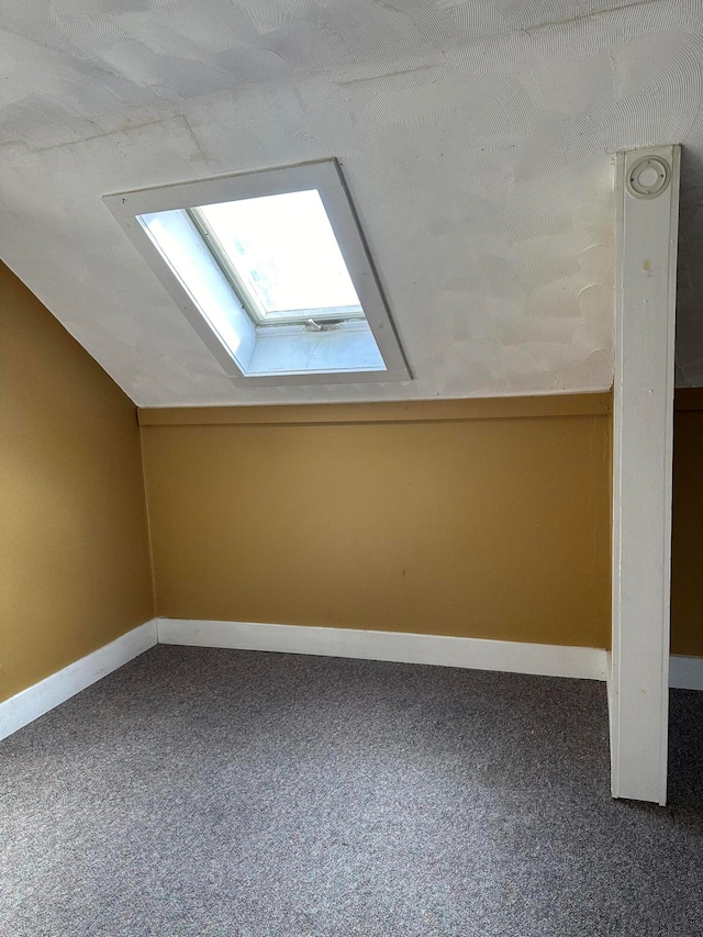 bonus room featuring lofted ceiling with skylight and carpet