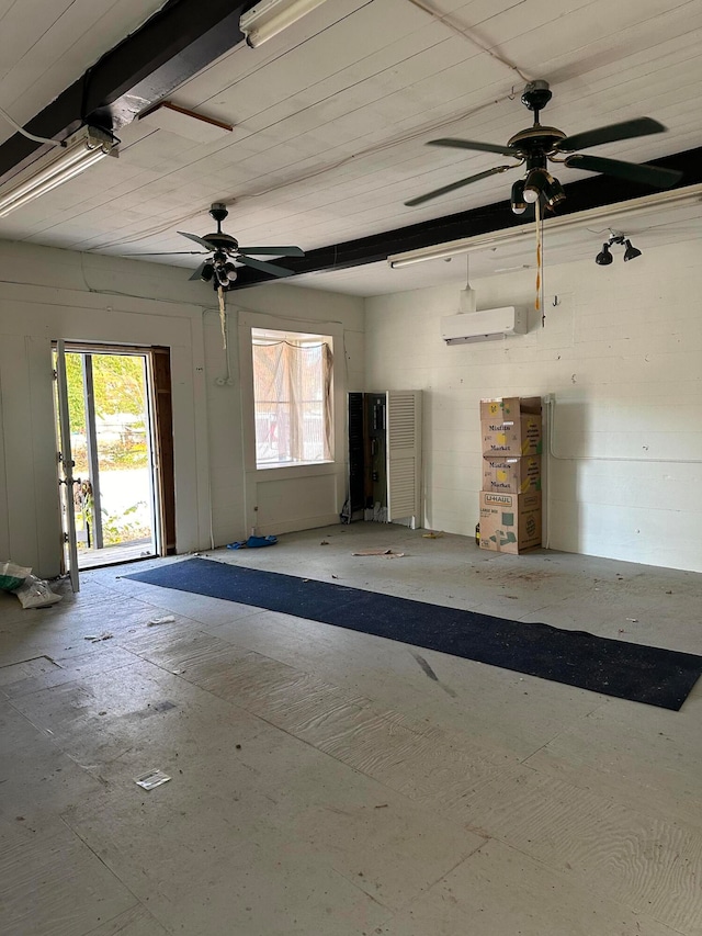 spare room with a wall unit AC, ceiling fan, and a wealth of natural light