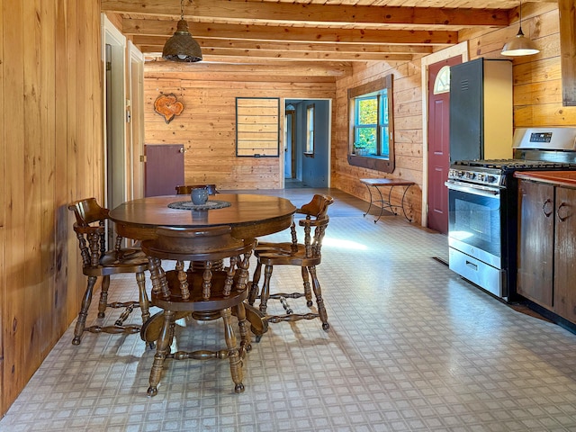 dining space with wood walls and beamed ceiling